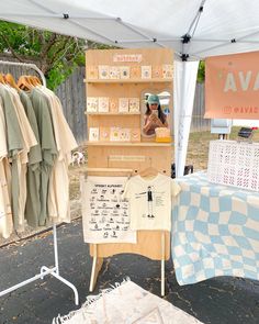 a woman is standing in front of a booth selling t - shirts