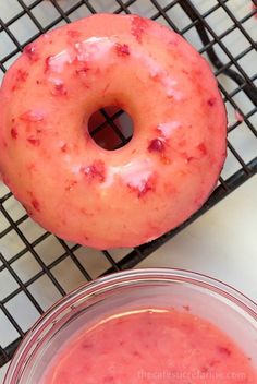 a doughnut sitting on top of a cooling rack next to a bowl of sauce