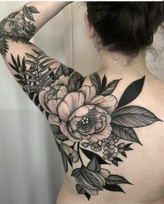 the back of a woman's shoulder with flowers and leaves tattooed on her arm