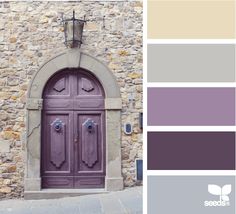 a purple door is in front of a stone building with a light fixture above it