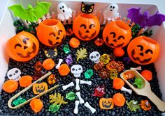 an assortment of halloween decorations in a white box with black rocks and pebbles on the ground