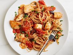 a white plate topped with pasta covered in marinara sauce and tofu cubes