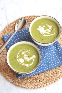 two bowls filled with green soup on top of a blue napkin