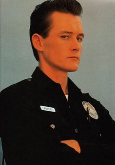 a police officer in uniform posing for a photo with his arms crossed and looking off to the side