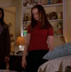 two women standing next to each other in a bedroom