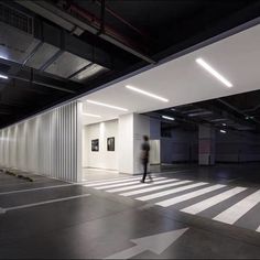 an empty parking garage with a person walking in the center and light shining on the floor