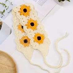 crocheted sunflowers are on the table next to a bowl and book