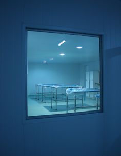 an empty room with tables and chairs seen through a window at the end of the room