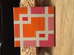 an orange, pink and white square is sitting on a table next to a basket