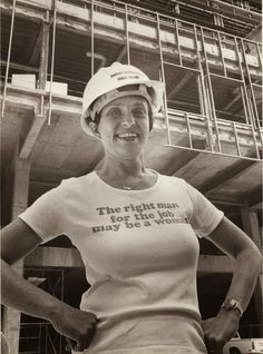 a woman wearing a hard hat standing in front of a building