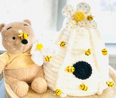 a teddy bear sitting next to a knitted beehive with bees around it