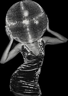 a woman holding a disco ball on her head