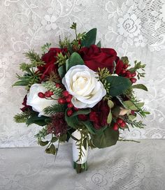 a bridal bouquet with red and white flowers on a lace tableclothed background