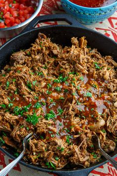 a skillet filled with pulled pork and gravy on top of a table