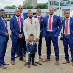 a group of men standing next to each other wearing suits and ties with a small boy in the middle