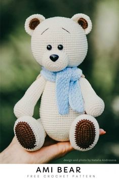 a crocheted white teddy bear wearing a blue scarf