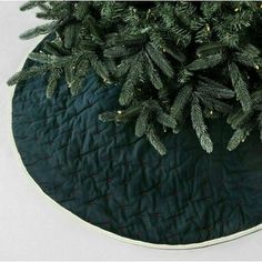 a close up of a christmas tree skirt on a round tablecloth with pine needles