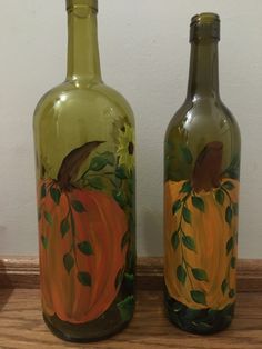 two glass bottles with painted pumpkins on them