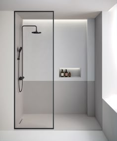 a white bathroom with a shower and two bottles on the shelf in front of it