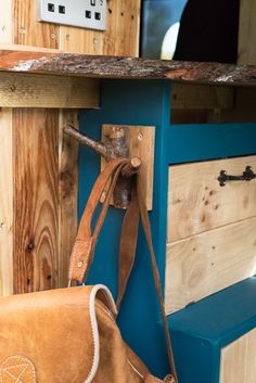 a brown bag sitting on top of a wooden bench next to a blue wall with a tv