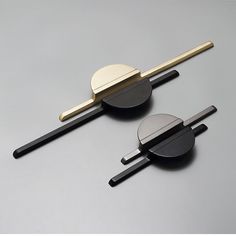 two pieces of metal sitting next to each other on top of a gray surface with black and gold accents