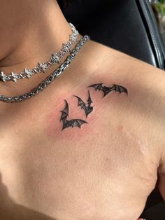 a woman's chest with three bats tattoo on the left side of her chest