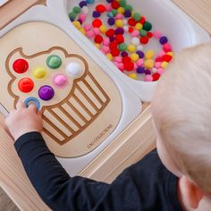 a young boy is playing with an activity tray