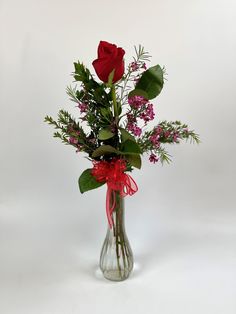 a vase filled with red roses and greenery