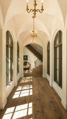 the sun shines through windows in an elegant hallway with wood floors and chandelier