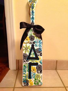 a decorated toothbrush holder with a black bow on the top and letter a on the bottom