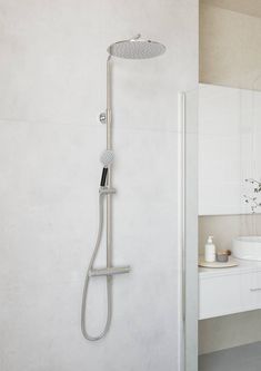 a shower head and hand held shower faucet in a modern bathroom with white walls