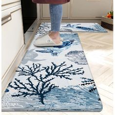 a woman standing on top of a rug in a kitchen next to an oven and sink