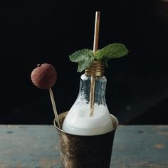 a glass filled with milk and two strawberries on top of it, sitting on a wooden table