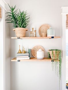 two wooden shelves with plants and other decorative items on them in a white walled room