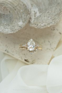 an engagement ring sitting on top of a rock next to a piece of white fabric