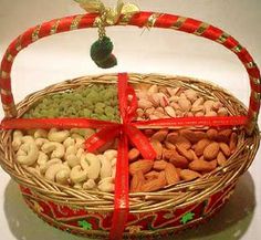 a wicker basket filled with nuts and almonds wrapped in red ribbon, sitting on a white surface