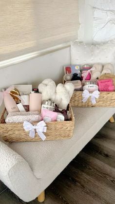 two baskets filled with items sitting on top of a white couch next to a window