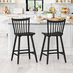 two black bar stools sit in front of an island with white cabinets and marble countertops