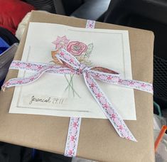 a gift wrapped in brown paper with pink flowers on it