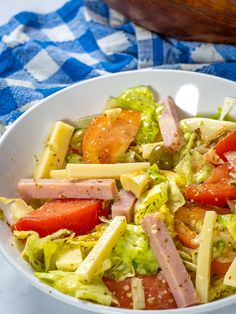 a white bowl filled with salad on top of a blue and white checkered table cloth