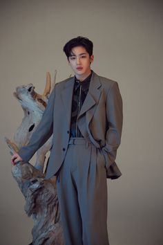 a man standing next to a deer statue wearing a gray suit and black turtle neck sweater