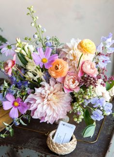 a bouquet of flowers sitting on top of a wooden table next to a card holder