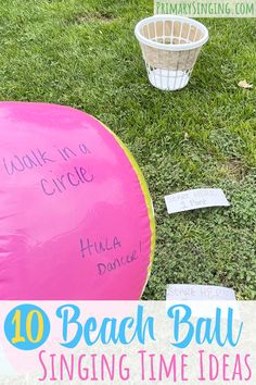 a pink beach ball sitting on top of a lush green field next to a basket