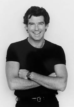 a black and white photo of a smiling man with his arms crossed in front of him