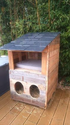 a dog house made out of pallet wood with two holes in the roof and one hole at the top