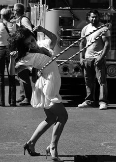 a woman is dancing on the street in front of a firetruck and people