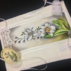 a white tray with flowers on it next to some ribbon and a piece of paper