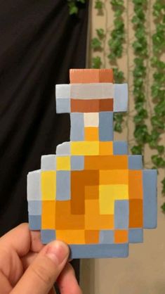 a hand holding a piece of art made out of lego blocks