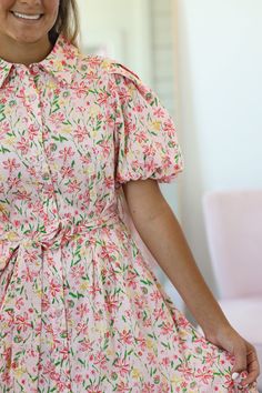 Our Iva Floral Dress displays a beautiful floral print with shades of pink, green, and yellow on a light pink background. This collared button-down dress has working buttons the full length of the dress and is nursing friendly. A waist tie adds the perfect detail. A wide tier with a tiny ruffle detail makes up the hemline and completes the dainty style of the dress. This is such an adorable dress for all occasions! - Collared button-down - Short puff sleeve - Working buttons full length of dress Light Pink Background, Dainty Style, Dress Display, Short Puff Sleeve, Skirts For Kids, Boys Denim, Nursing Friendly, Sweater Dress Midi, Button Down Dress