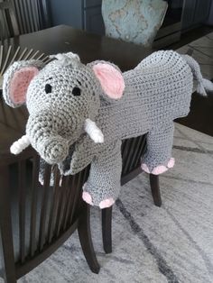 a crocheted elephant sitting on top of a wooden chair next to a table